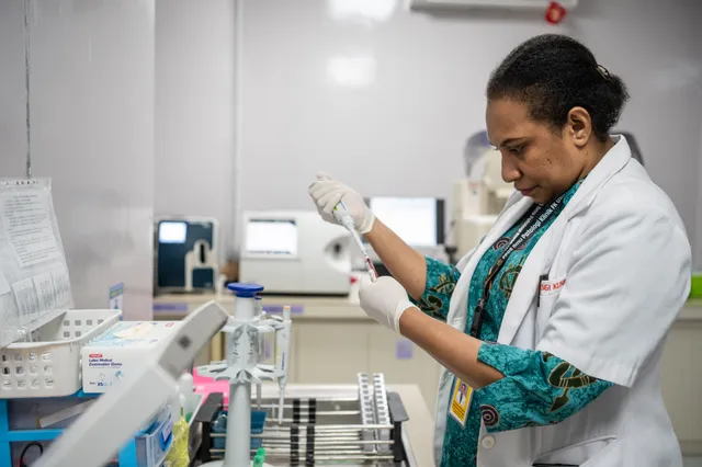 A medical laboratory technician draws samples with a micropipette in a clinical pathology lab